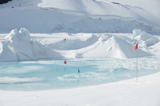 The landscape is constantly changing. Just a day or two earlier, this pool of water didn\'t exist, and the trail (marked by red and green flags) went right across it. (click to enlarge)