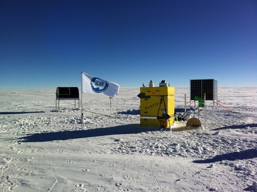 The completed observatory at Ridge A showing the HEAT telescope (at left) nestling under its fibreglass cover, with the Instrument Module and solar panels. The flag is that of the Scientific Committee on Antarctic Research. The Engine Module is out of the field of view. CREDIT: Craig Kulesa. (click to enlarge)